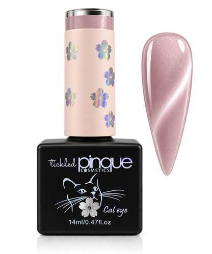 Tickled Pinque Cosmetics 'Cateye' nail polish in a black bottle with a pale pink cap decorated with iridescent flowers, shown next to a matching pink cat-eye coated nail swatch on a white background.