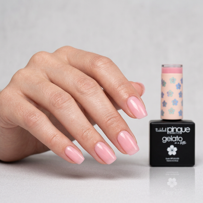 A hand with neatly manicured pink nails is shown beside a bottle of gel nail polish. The polish appears to be the product being sold, and the bottle label reads 'Tiffany Pinque gelato' with a floral cap design.