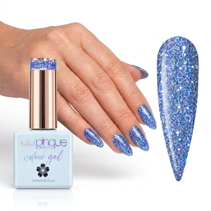 A bottle of Tiki Tiki Cosmetics Colour Gel nail polish with a metallic rose gold cap, shown next to a hand with blue glitter nails and a large nail swatch displaying the sparkling blue finish.